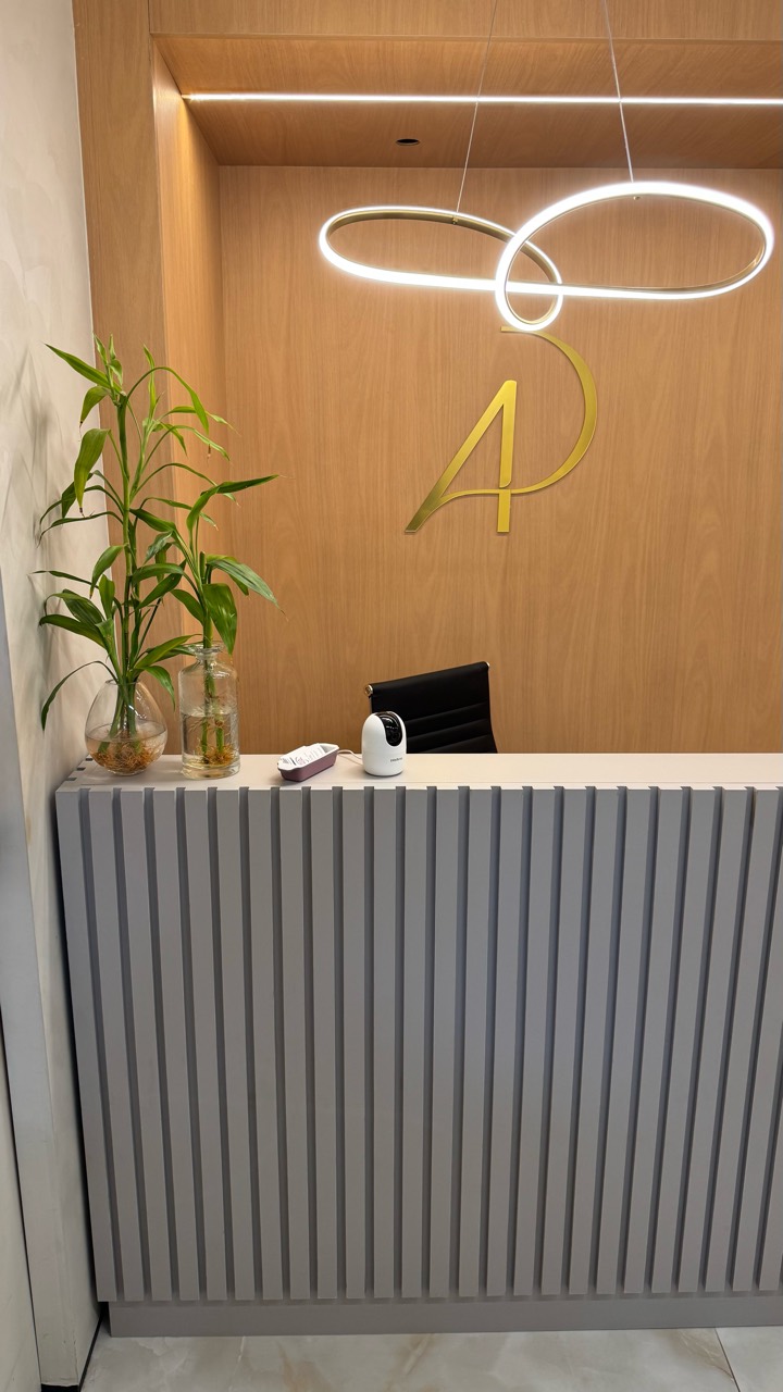 Balcão da recepção com monograma AP dourado e painel de madeira