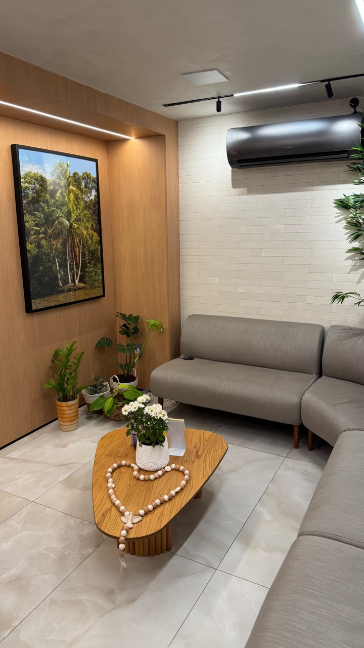 Sala de espera com sofá, plantas e mesa de madeira